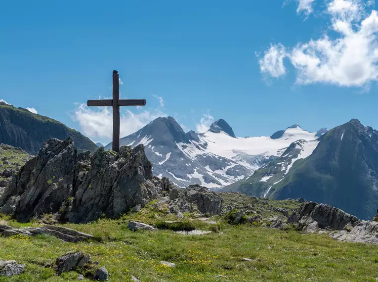 Holzkreuz auf einem Berggipfel mit Alpengipfeln und Gletscher im Hintergrund