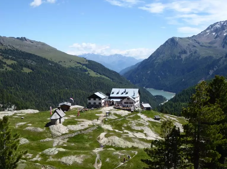 Die Zufallhütte im Martelltal vor einer Bergkulisse und See.