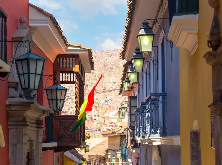 Schmale Straße in La Paz mit bunten Gebäuden und bolivianischer Fahne.