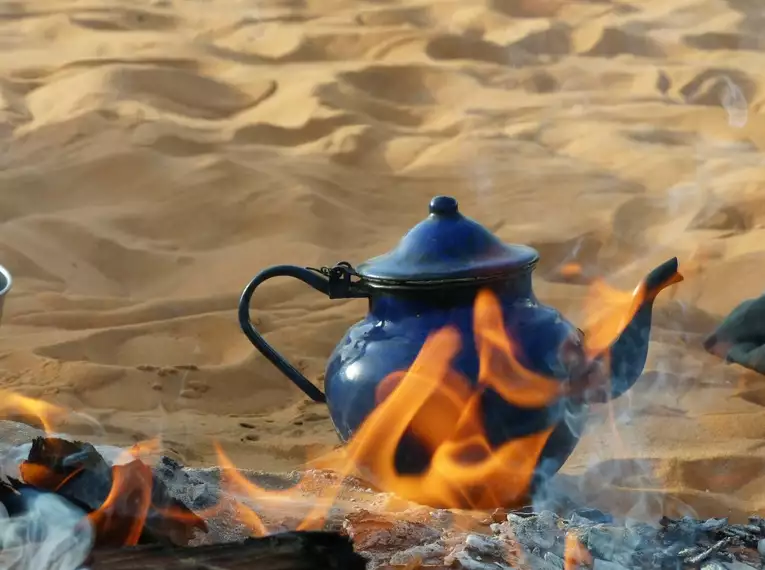 Teekanne über offenem Feuer auf Sand in der Sahara