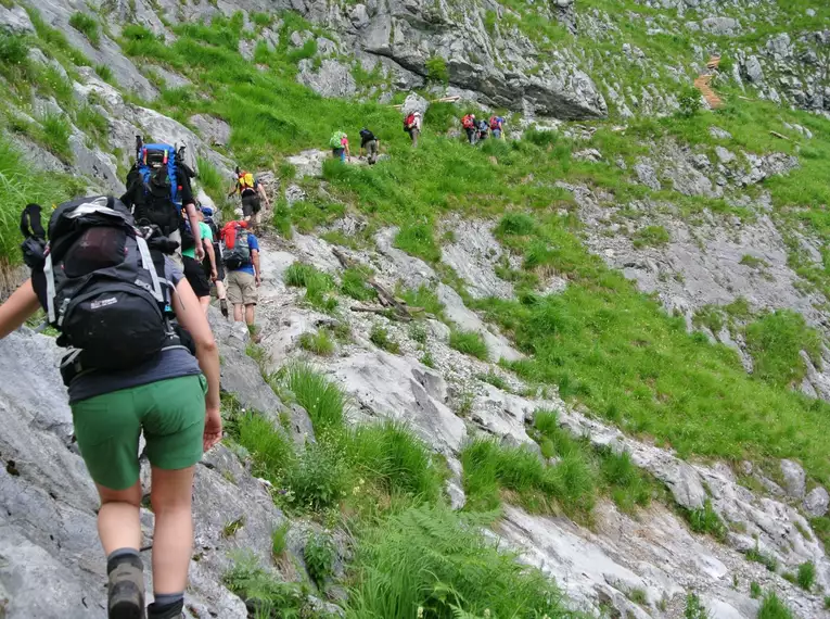 Gruppe von Wanderern auf steinigem Bergpfad im Berchtesgadener Land.