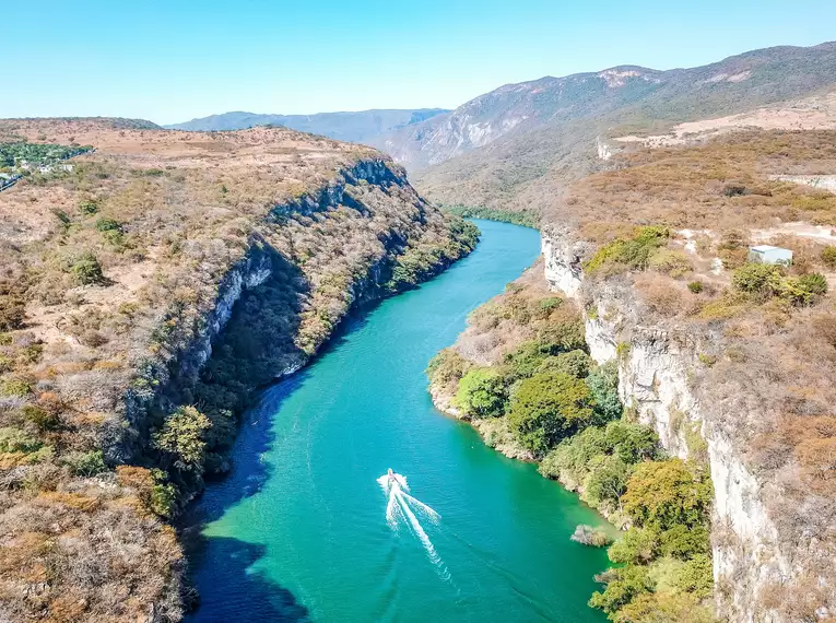 Ein Boot fährt auf dem türkisfarbenen Fluss im Cañon del Sumidero.