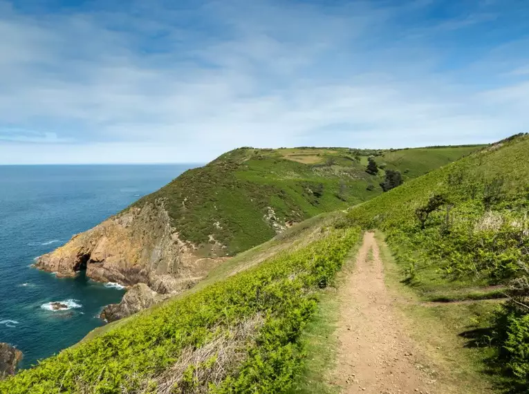 Grüner Wanderweg entlang der Küste auf Jersey mit Meerblick.