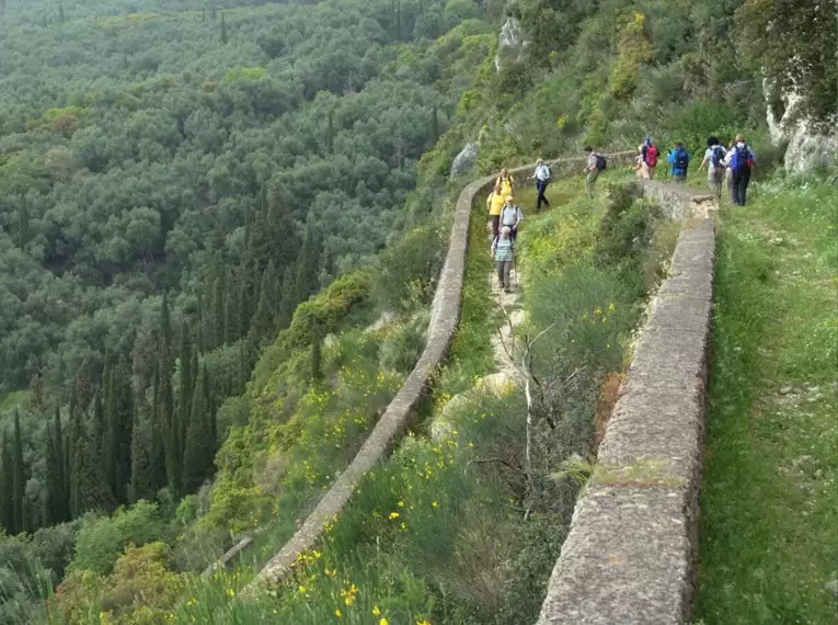 Eine Gruppe von Wanderern auf einem schmalen Pfad in Korfus grüner Landschaft.