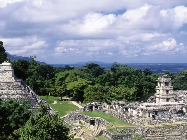 Maya-Ruinen von Palenque umgeben von üppigem Regenwald und Wolkenhimmel.