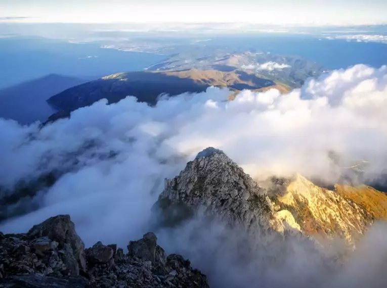 Berge von Wolken umgeben mit Blick auf die Küste bei Sonnenaufgang.