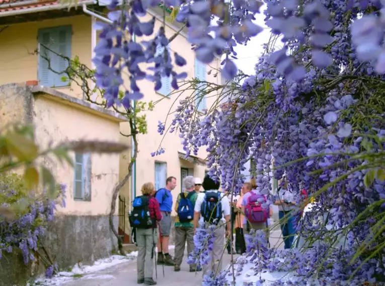 Eine Wandergruppe besichtigt die blühenden Straßen eines Dorfes auf Korfu.