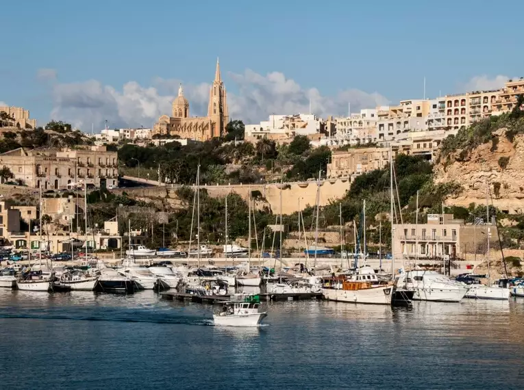 Blick auf den Hafen von Gozo mit Booten und Stadt im Hintergrund.