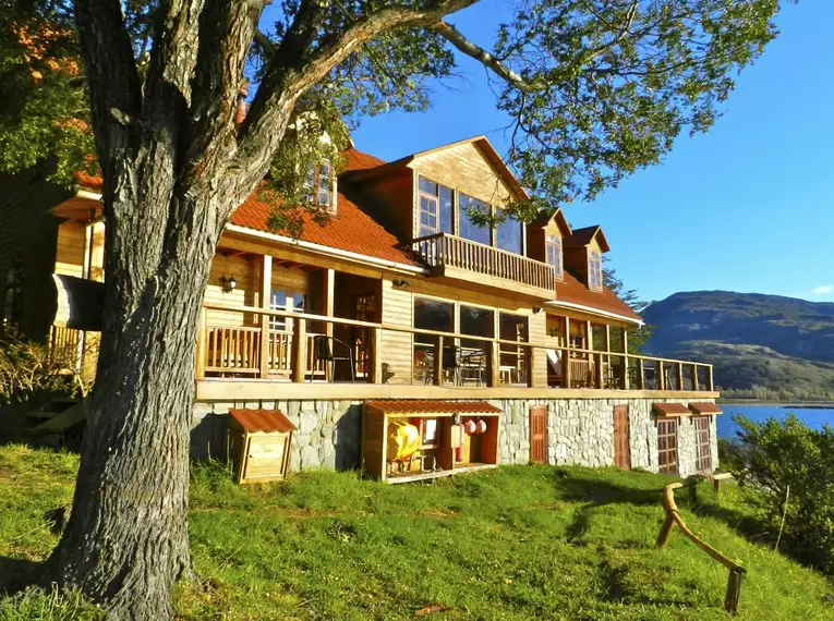 Idyllische Lodge am See in Patagonien mit Holzveranda und Bergblick.