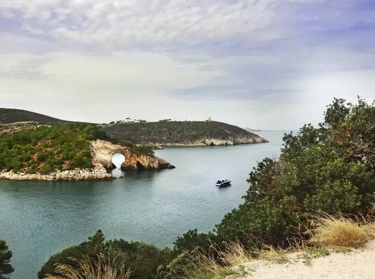 Malerische Bucht in Apulien mit Felsen und Boot im Wasser.