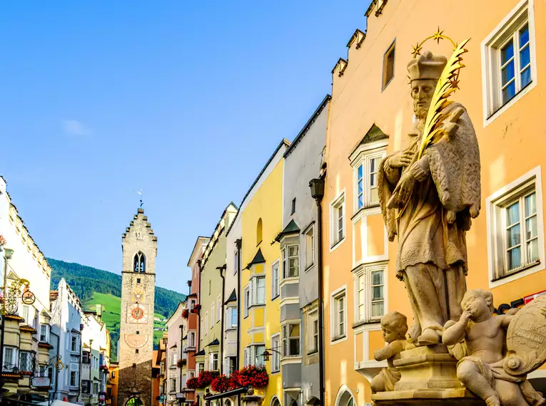 Historische Altstadt von Sterzing mit bunten Gebäuden und Statue.