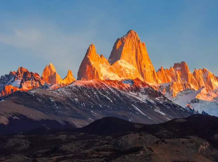 Der Fitz Roy erstrahlt im goldenen Abendlicht, Schnee bedeckt die Spitzen.