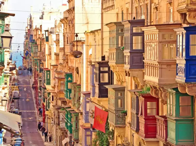 Bunte maltesische Balkone entlang einer sonnigen Straße in Valletta, Malta.