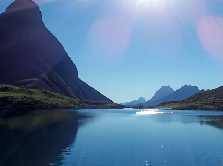 Bergsee mit umliegender Gebirgskulisse im Sonnenlicht im Allgäu