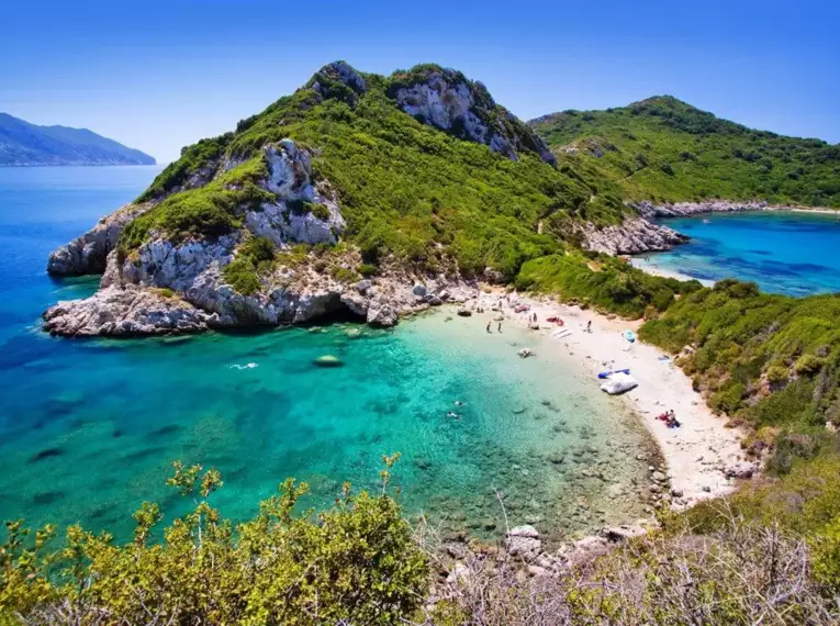 Grüne Hügel und türkisfarbenes Wasser auf Korfu mit Strandblick.