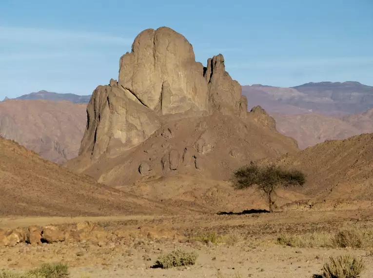 Ein imposanter Felsen in der Wüste von Algerien, umgeben von karger Landschaft.