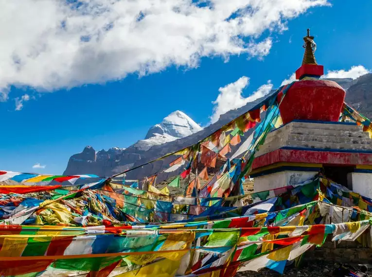 Mount Kailash in Tibet hinter bunten Gebetsfahnen und einer Stupa.