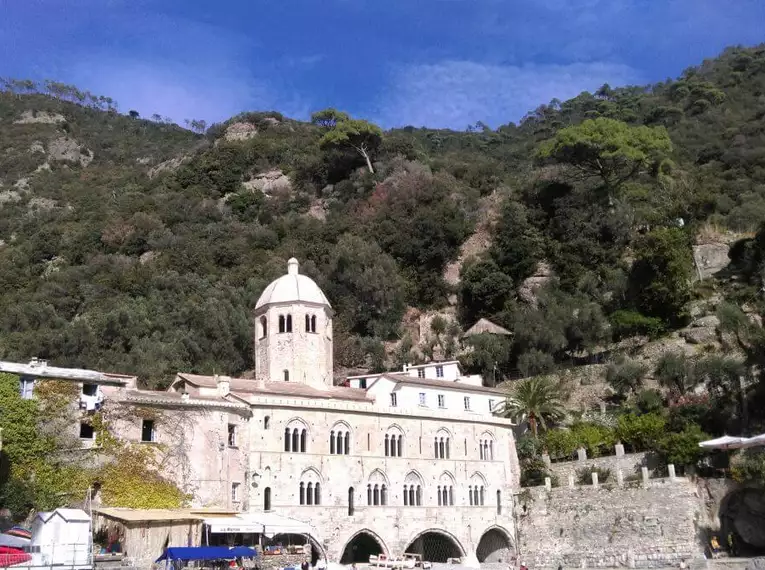 Mittelalterliche Abtei San Fruttuoso umgeben von Hügeln und Grün.