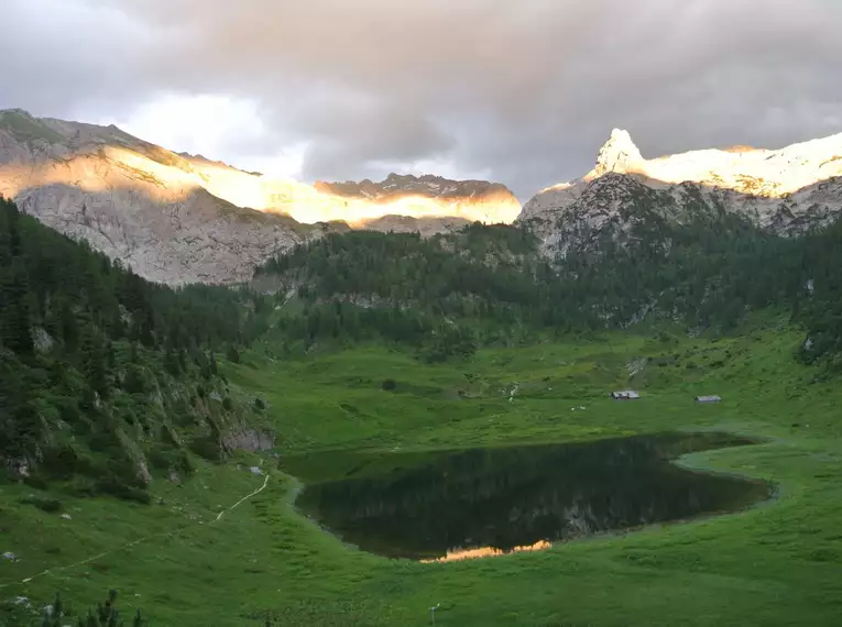 Ein idyllischer Bergsee umgeben von Gipfeln im Abendlicht.