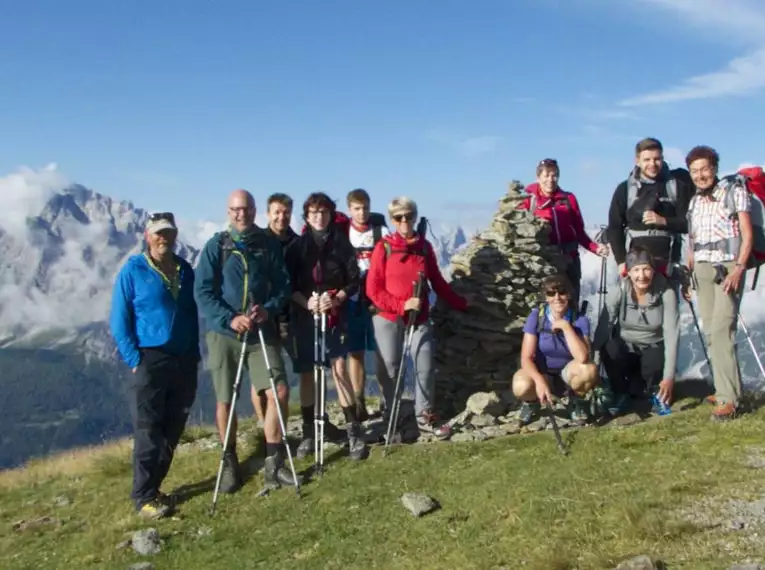 Eine Gruppe von Wanderern auf einem Berggipfel in Südtirol mit Ausblick auf die Alpen.