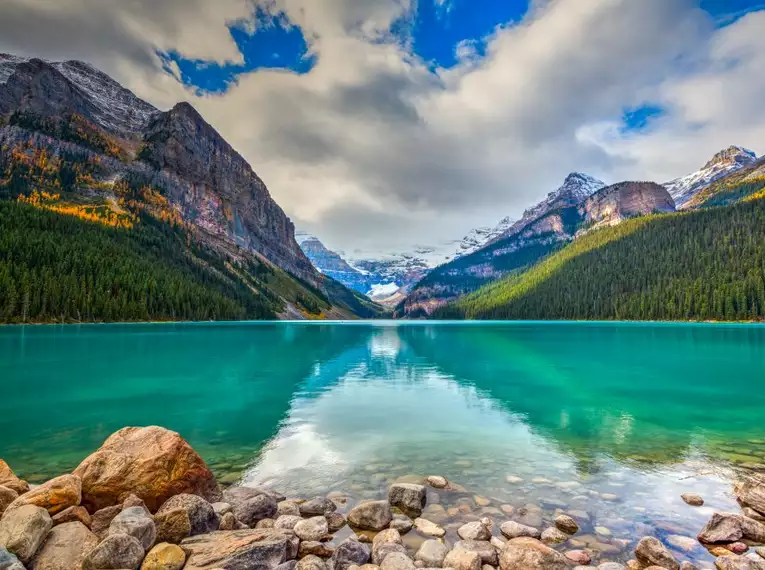 Ein smaragdgrüner See umgeben von schneebedeckten Bergen in den Rockies.