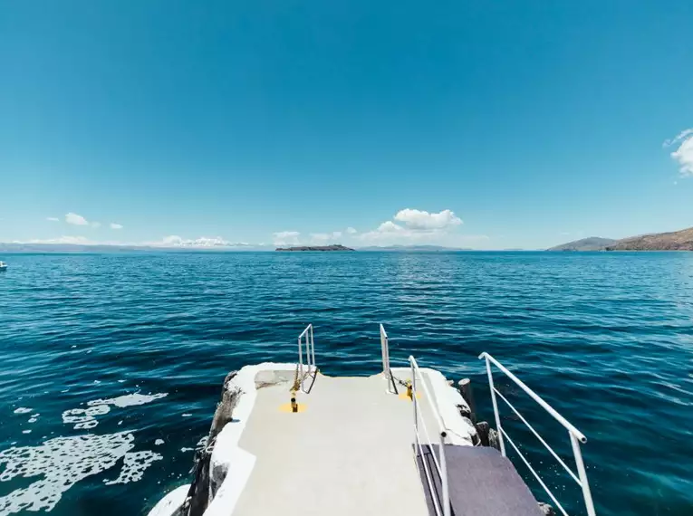 Ein Steg führt ins azurblaue Wasser eines Sees, umgeben von einer weiten Landschaft. Klare Sicht und ruhige Atmosphäre.