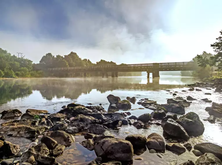 Brücke über einen Fluss mit Nebel und Felsen entlang des Great Glen Way.