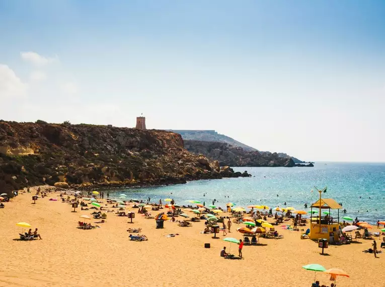 Strand mit bunten Sonnenschirmen und Besuchern auf Malta