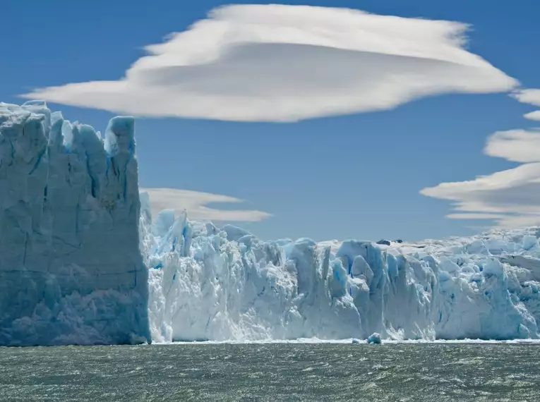 Der imposante Perito Moreno Gletscher in Patagonien vor blauem Himmel und Wolken.